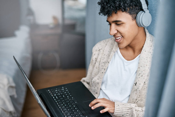 Work from home, play at home. a young man using a laptop and headphones at home - Photo, Image