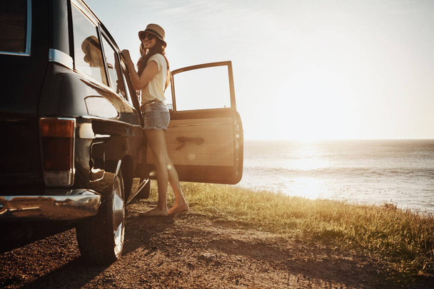 Nothing quite as relaxing as a road trip. Portrait of a young woman enjoying a road trip along the coast - Foto, imagen