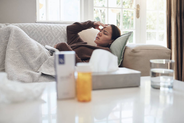 Γιατί με έπιασε το μικρόβιο; μια νεαρή γυναίκα ξαπλωμένη σε έναν καναπέ, ενώ αισθάνεται άρρωστος στο σπίτι - Φωτογραφία, εικόνα