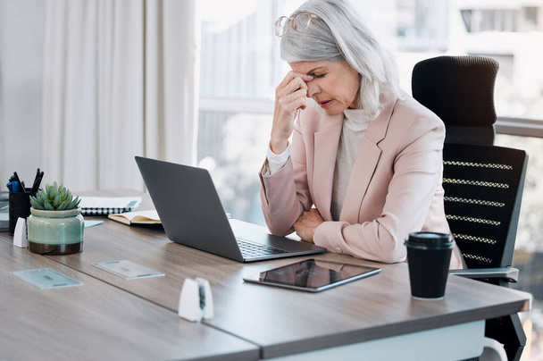 Έχω τόσο άσχημο πονοκέφαλο. μια ώριμη επιχειρηματίας που κάθεται μόνη στο γραφείο και αισθάνεται στρεσαρισμένη ενώ χρησιμοποιεί το laptop της - Φωτογραφία, εικόνα