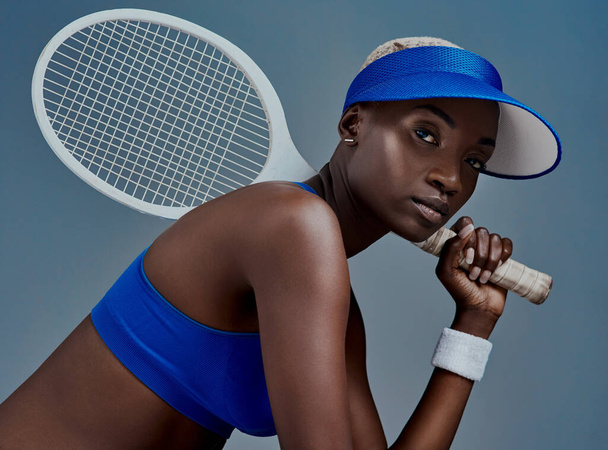 I take the game serious. Studio shot of a sporty young woman posing with a tennis racket against a grey background - Photo, Image
