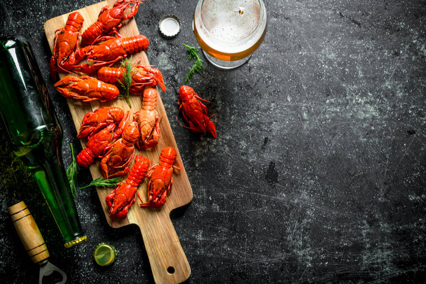 Boiled crayfish with a bottle of beer. On dark rustic background - 写真・画像