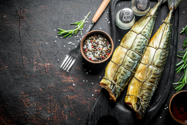 Smoked mackerel with spices and rosemary. On dark rustic background - Foto, afbeelding
