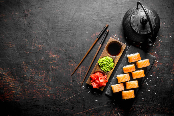 Philadelphia sushi roll on a stone stand with ginger, wasabi and soy sauce. On dark rustic background - Foto, imagen