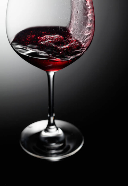 Primo piano di vino rosso versando su uno sfondo nero. - Foto, immagini