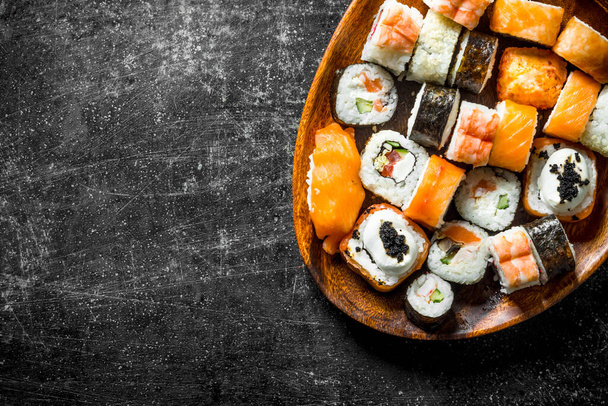 Sushi rolls with salmon and vegetables on a wooden plate. On dark rustic background - Fotografie, Obrázek