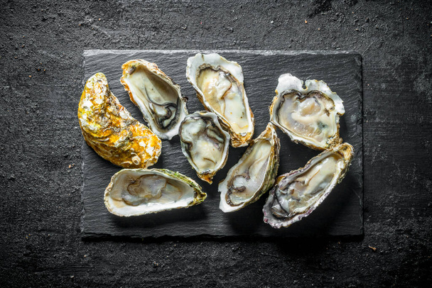 Fresh oysters ina stone Board. On black rustic background - Foto, imagen