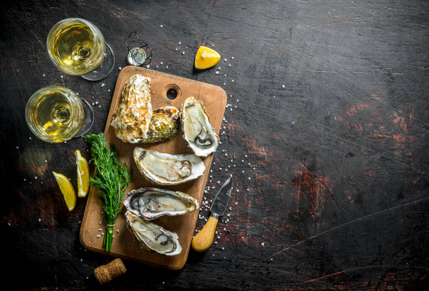 Fresh delicious oysters with white wine, lemon and dill. On dark rustic background - Foto, Imagen
