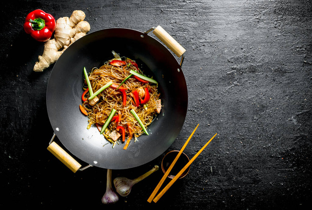 Delicious cellophane noodles in a frying pan wok with chopsticks. On black rustic background - Fotoğraf, Görsel