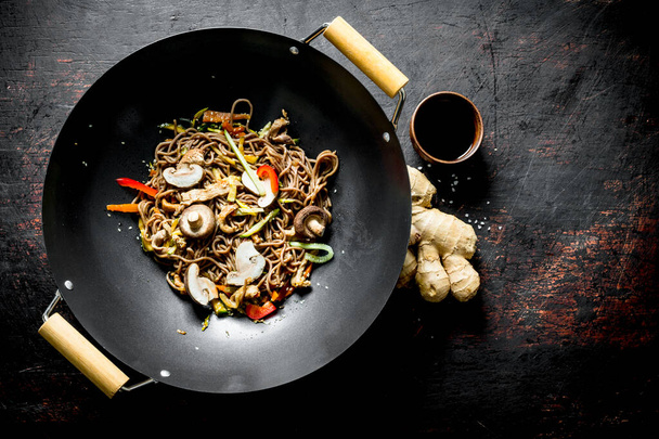 Chinese wok. Asian soba noodles with vegetables and mushrooms. On dark rustic background - Foto, Bild