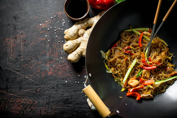 Freshly cooked Chinese noodles wok funchoza with salmon, vegetables and sauce. On dark rustic background - Zdjęcie, obraz