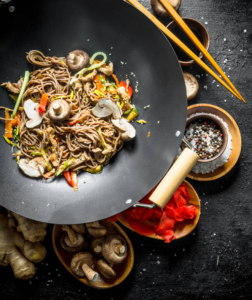 Delicious Asian soba noodles with spices, mushrooms and ginger. On black rustic background - Photo, image