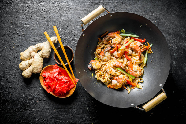 Delicious Chinese wok Udon noodles with fresh vegetables, sauce and shrimp. On black rustic background - Fotó, kép