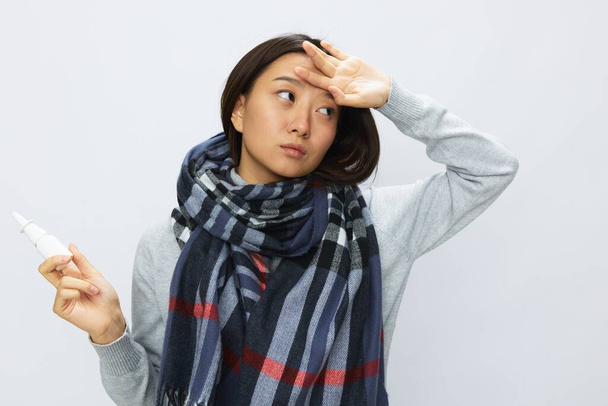 Femme asiatique tenant la main au mal de tête grippe froide avec nez bouché tenant allergie et virus pulvérisation nasale avec mal de gorge sur fond blanc. Photo de haute qualité - Photo, image