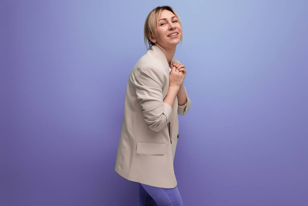 close-up van een positieve glimlachende blonde zakenvrouw in een jas succesvol in het werk op de achtergrond met kopieerruimte. - Foto, afbeelding