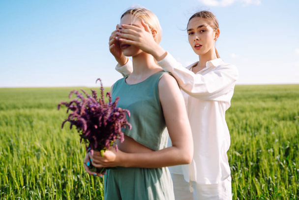 Two fashion woman in the green field. Fashion concept. Beautiful figures. Summer concept. - Foto, imagen