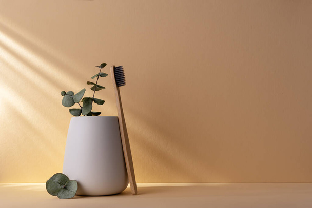 Eco-friendly bamboo toothbrush in a white glass. Zero waste, plastic free, sustainable lifestyle concept. - Фото, изображение
