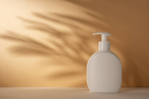 White pump bottle with palm leaves shadows on background. Mock up for natural grooming product. - Zdjęcie, obraz