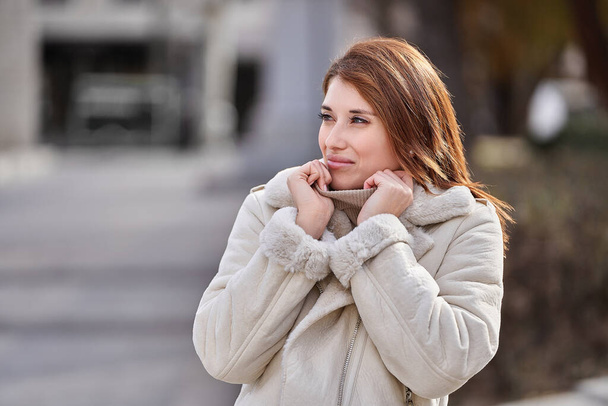 Стильна жінка в зимовому одязі, дивлячись далеко, стоячи на вулиці
. - Фото, зображення