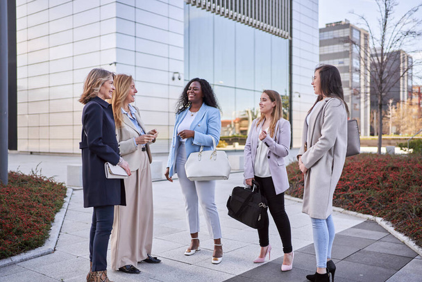 Female coworkers talking and smiling while meeting outdoors. Business concept. - Photo, Image