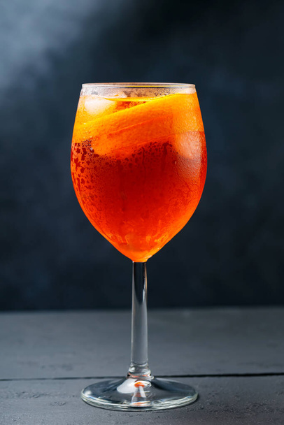 Aperol Spritz cocktail on dark wooden planks. Cocktail Aperol Spritz with oranges and ice cubes in glass. Traditional italian aperitif cocktail - Φωτογραφία, εικόνα