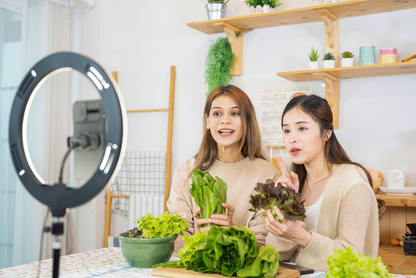 Junge Bloggerinnen zeigen Salat mit gesunden Lebensmitteln für das Gesundheitswesen. Team mit Smartphone Live-Online-Verkauf von Lebensmitteln fit Körper zum Abnehmen. - Foto, Bild