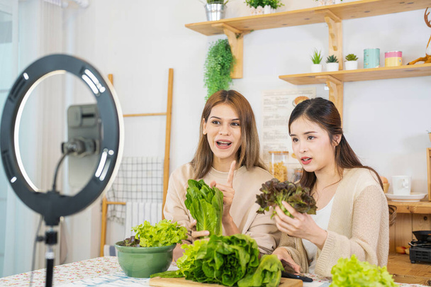 jeunes blogueuses montrant une salade d'aliments sains pour les soins de santé. équipe utilisant le téléphone portable intelligent en direct en ligne la vente de nourriture corps apte pour perdre du poids. - Photo, image