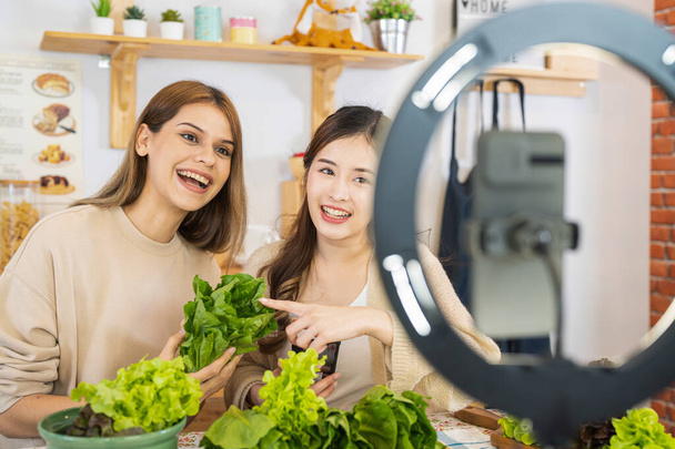 Junge Bloggerinnen zeigen Salat mit gesunden Lebensmitteln für das Gesundheitswesen. Team mit Smartphone Live-Online-Verkauf von Lebensmitteln fit Körper zum Abnehmen. - Foto, Bild
