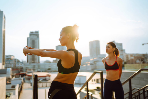 Two Young woman in sports outfit doing exercises outdoors in the morning.  Sport, Active life, sports training, healthy lifestyle. - Φωτογραφία, εικόνα