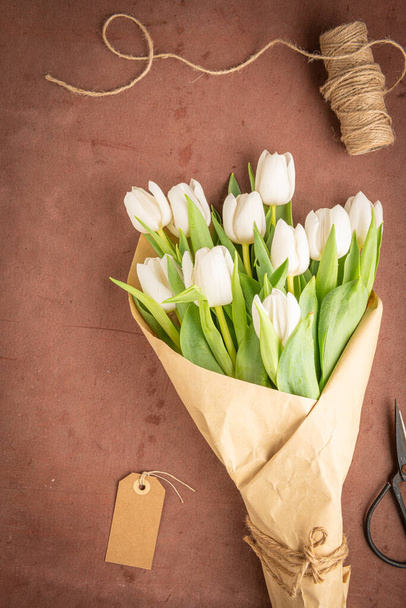 Bouquet of white tulips on a red cement background, copy space. Easter. Top view - Фото, зображення