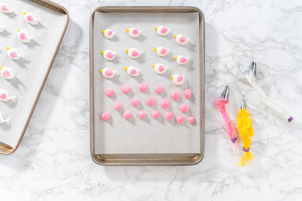 Piping meringue with piping bags into the baking sheet lined with parchment paper to bake Easter meringue cookies. - Valokuva, kuva