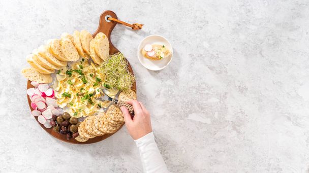 Deitado. Placa de manteiga com legumes e pão em uma tábua de corte de madeira redonda. - Foto, Imagem