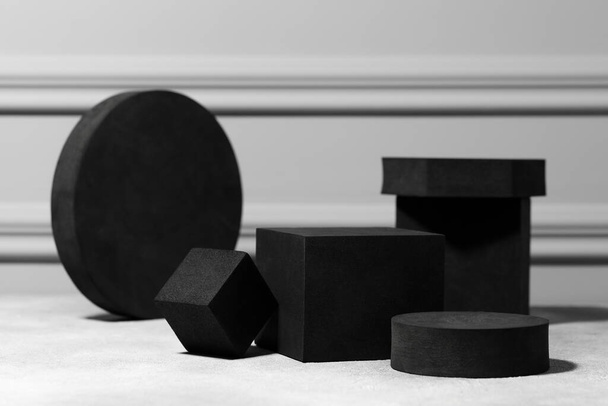 Black geometric figures on light grey table. Stylish presentation for product - Foto, Bild