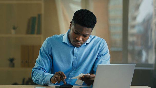 Young African american businessman man employee male count incomes bills manage personal budget use calculator calculate business expenses credit debt money balance managing finances financial ecomomy - Foto, Imagem