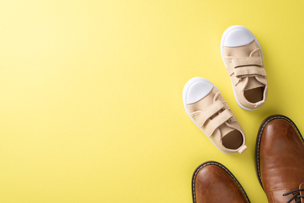 Father's Day idea with cute son and dad. Top view of leather shoes and baby sneakers on yellow background with space for text or advert - Foto, imagen