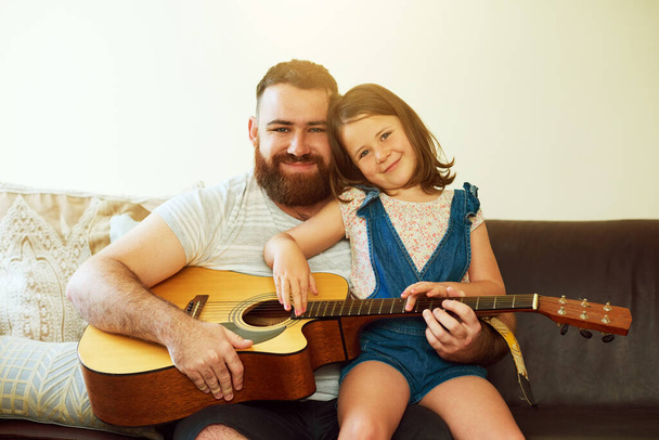 Apámtól örököltem a zene iránti szeretetemet. egy aranyos kislány gitározik az apjával otthon. - Fotó, kép