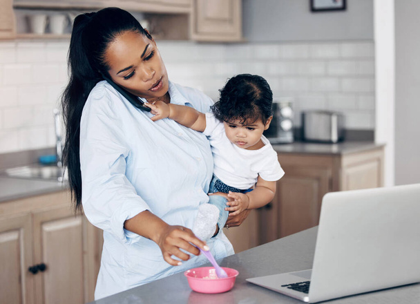 ¿Puedes llamar cuando ya haya comido? una madre joven alimentando a su bebé mientras usa un portátil en casa - Foto, Imagen