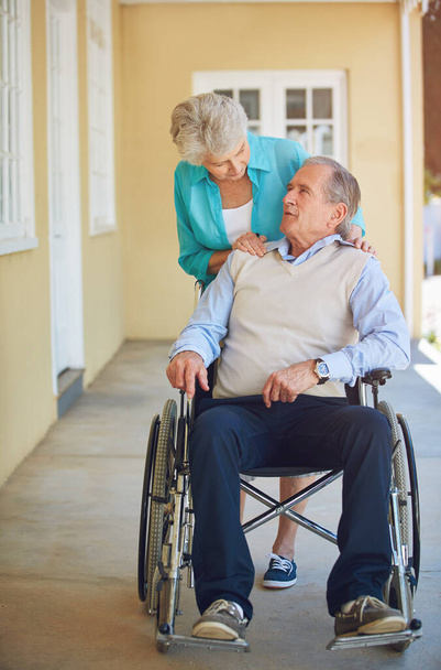 Talking, old woman or senior man wheelchair in retirement or nursing home helping husband for support. Wellness, couple or elderly wife pushing a mature person with a disability in house or clinic. - Photo, Image