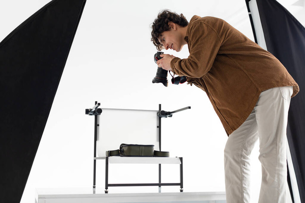 Creativity unleashed. Young photographer guy during content photoshoot, man working in photostudio with modern equipment, side view - Φωτογραφία, εικόνα