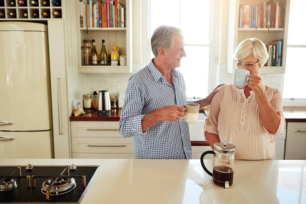 Szczęśliwy, kawa lub para starców rozmawiających w kuchni w domu lub korzystających z jakości porannego czasu razem. Miłość, uczucie lub dojrzały mężczyzna rozmawiający, relaksujący lub pijący herbatę espresso z kobietą w domu. - Zdjęcie, obraz