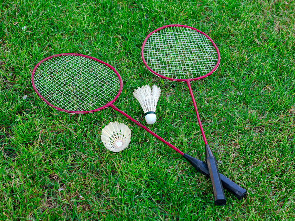 Две ракетки и два шаттла на зеленой траве - Фото, изображение