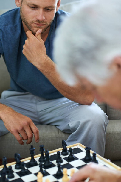 Papá tiene algunos movimientos de ajedrez interesantes. un padre y un hijo jugando una partida de ajedrez juntos en casa - Foto, Imagen