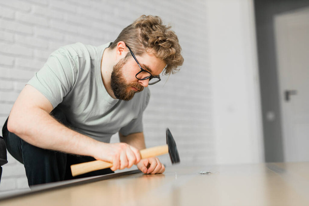Young attractive man assembles furniture - handwerker and interior objects - Foto, Bild