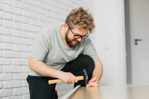 Bearded millennial man assemble his bookcase. He uses tools for furniture. Furniture for the interior room apartments - Фото, зображення
