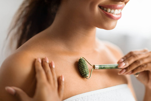 Smiling Black Woman Using Greenstone Jade Roller For Skin Care At Home, Young African American Female Massaging Chest Area, Making Anti-Aging Beauty Routine After Bath, Closeup Shot, Cropped - Foto, immagini