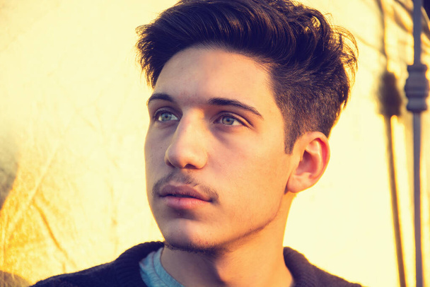 Headshot of one handsome young man with green eyes, looking away to a side, outdoor in a sunny day - Foto, Bild