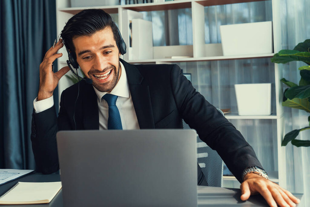Male call center operator or telesales representative siting at his office desk wearing headset and in conversation with client providing customer service support or making persuasive sale. fervent - Zdjęcie, obraz