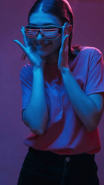 Cyberpunk portrait. Color light people. Satisfied stylish girl in party goggles at rave smiling having fun isolated on neon purple background. - Foto, afbeelding