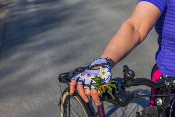 Close-up van de hand van de vrouw in sporthandschoenen met witte bloem. Zweden.  - Foto, afbeelding