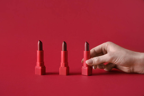 Woman with lipsticks on red background - Foto, Imagen